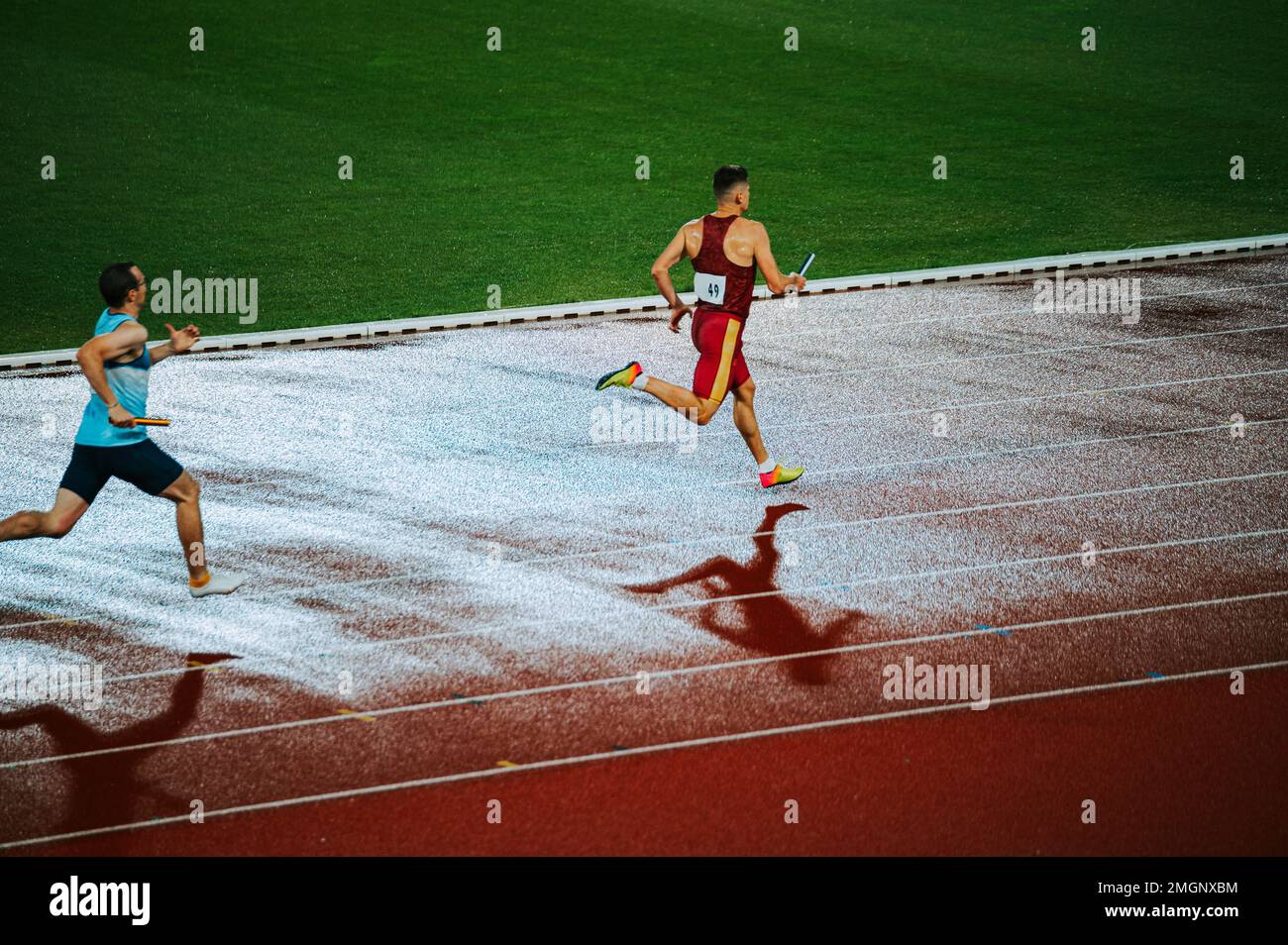 Alone sprinter captured in motion on the athletics track in rainy weather, showcasing determination and focus. Suitable for sports and fitness campaig Stock Photo