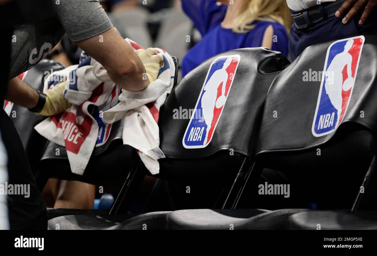 A San Antonio Spurs team attendant uses protective gear as she moves ball  off the court prior to an NBA basketball game between the San Antonio Spurs  and the New Orleans Pelicans