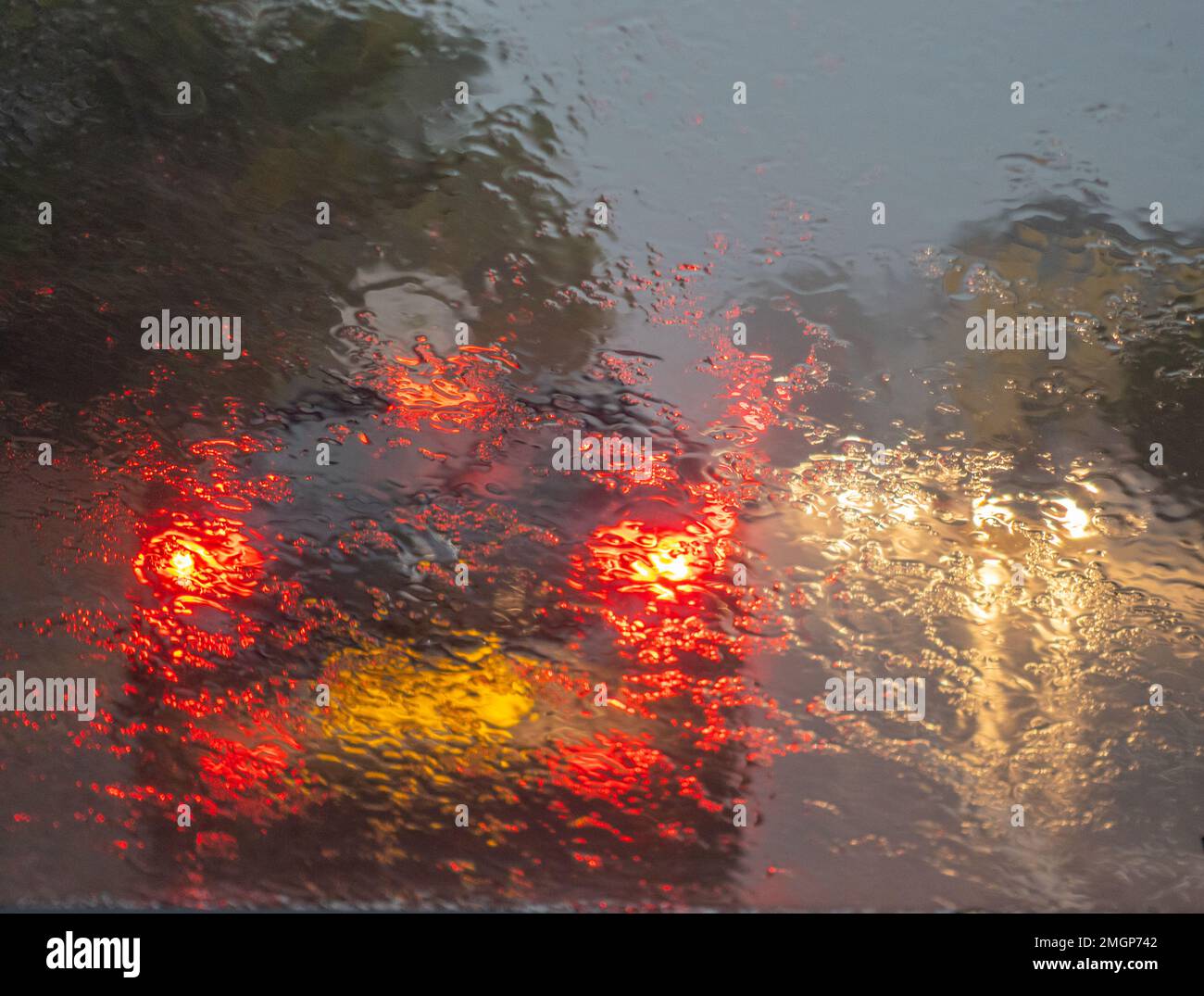 Red tail lights of a car through a wet windscreen during a rain storm