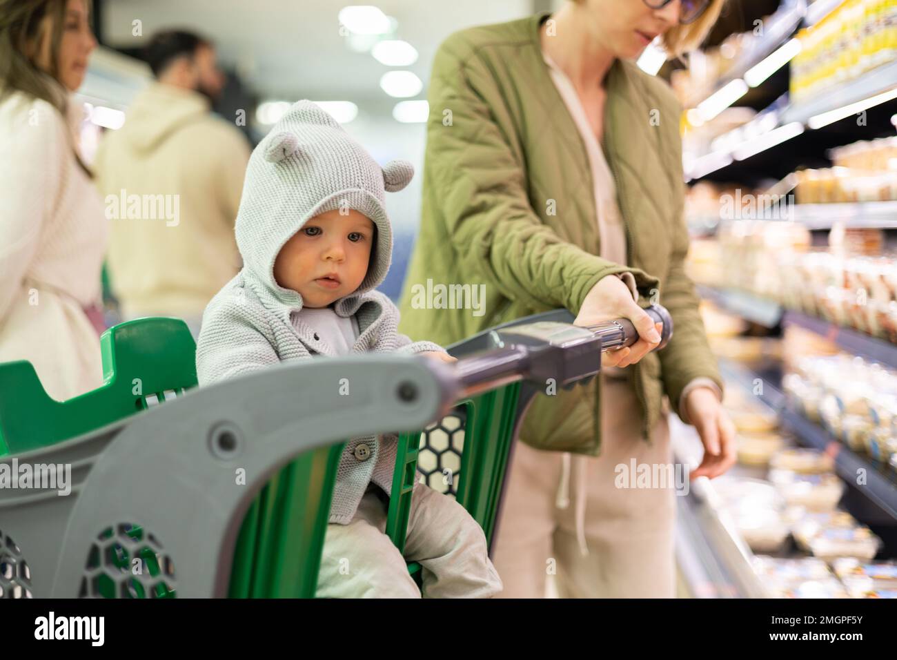 Casualy dressed mother choosing products in department of supermarket