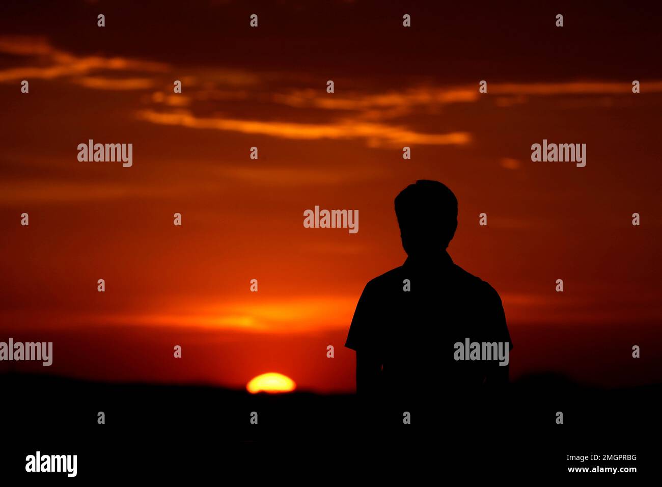 A man watches the sunset in Kansas City, Mo., Saturday, March 7, 2020