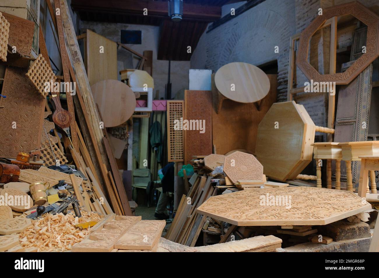Fez, Morocco - carpenter's shop in Fes el Bali medina. Work in progress at a woodshop. Octagon tabletop with carving. Wood shavings on the side. Stock Photo