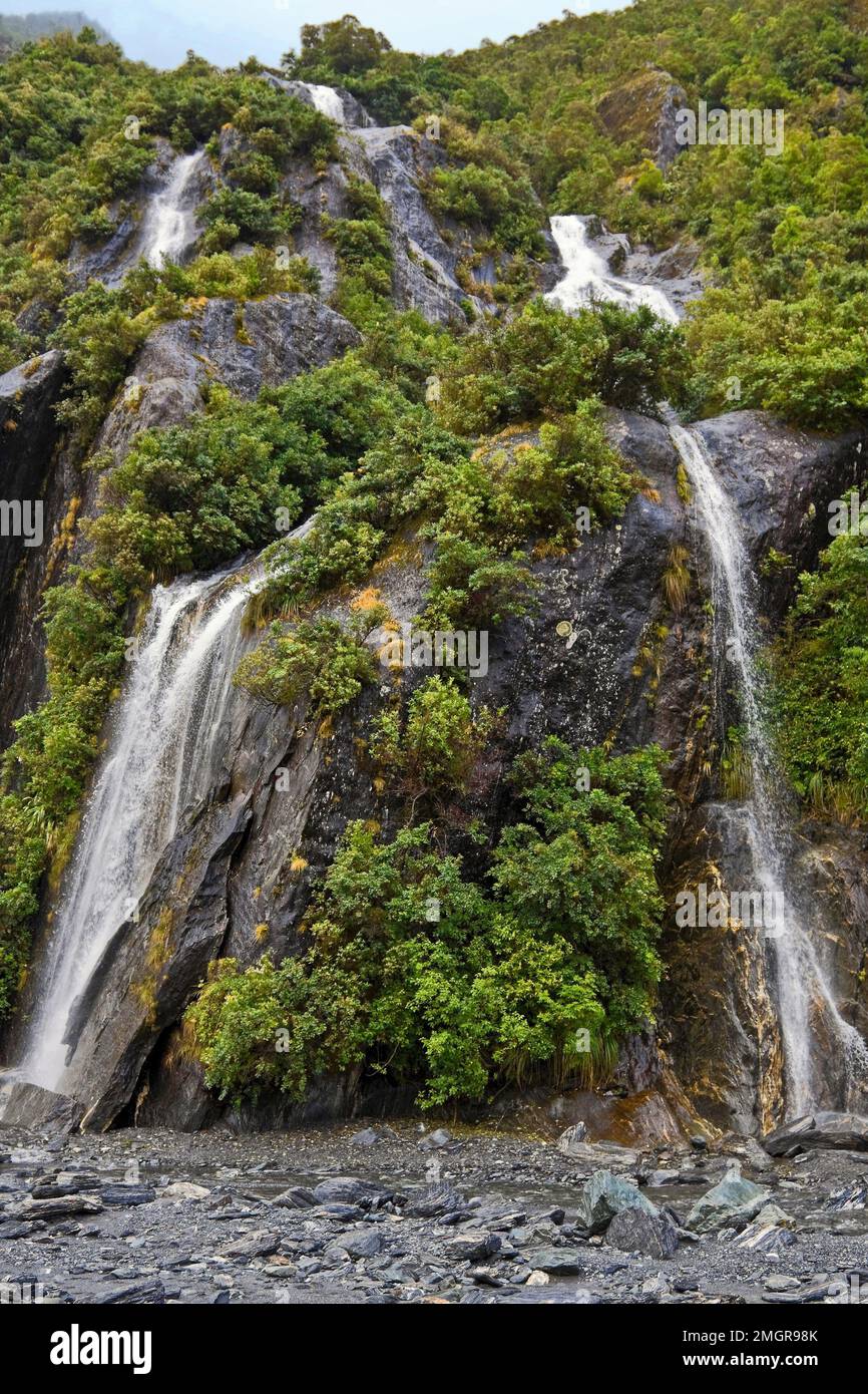 waterfalls, hillside, rock, green vegetation, nature, powerful,Franz Josef Glacier; Westland Tai Poutini NP, Franz Josef, New Zealand Stock Photo