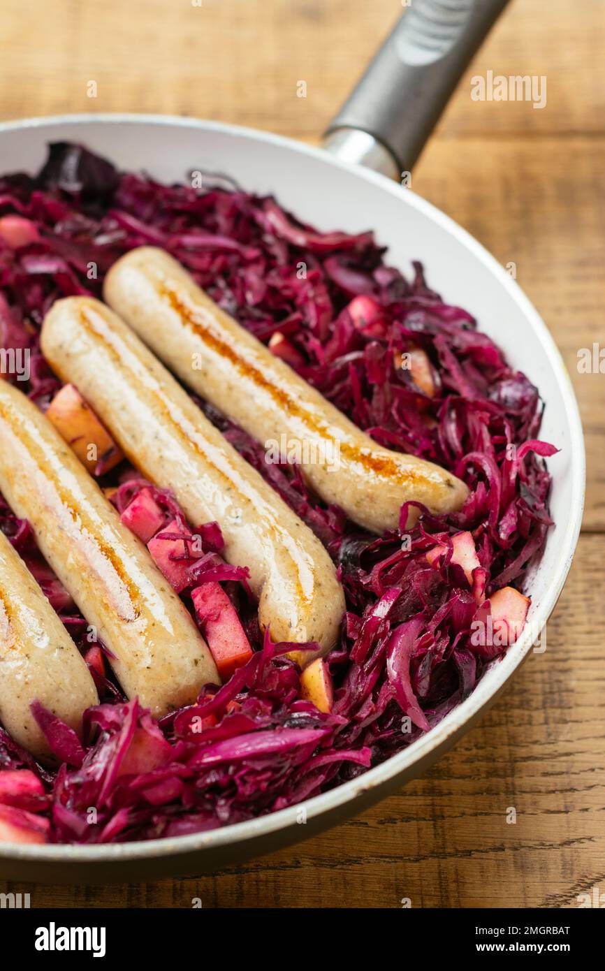 Frying pan with braised red cabbage with vegan sausages and apple