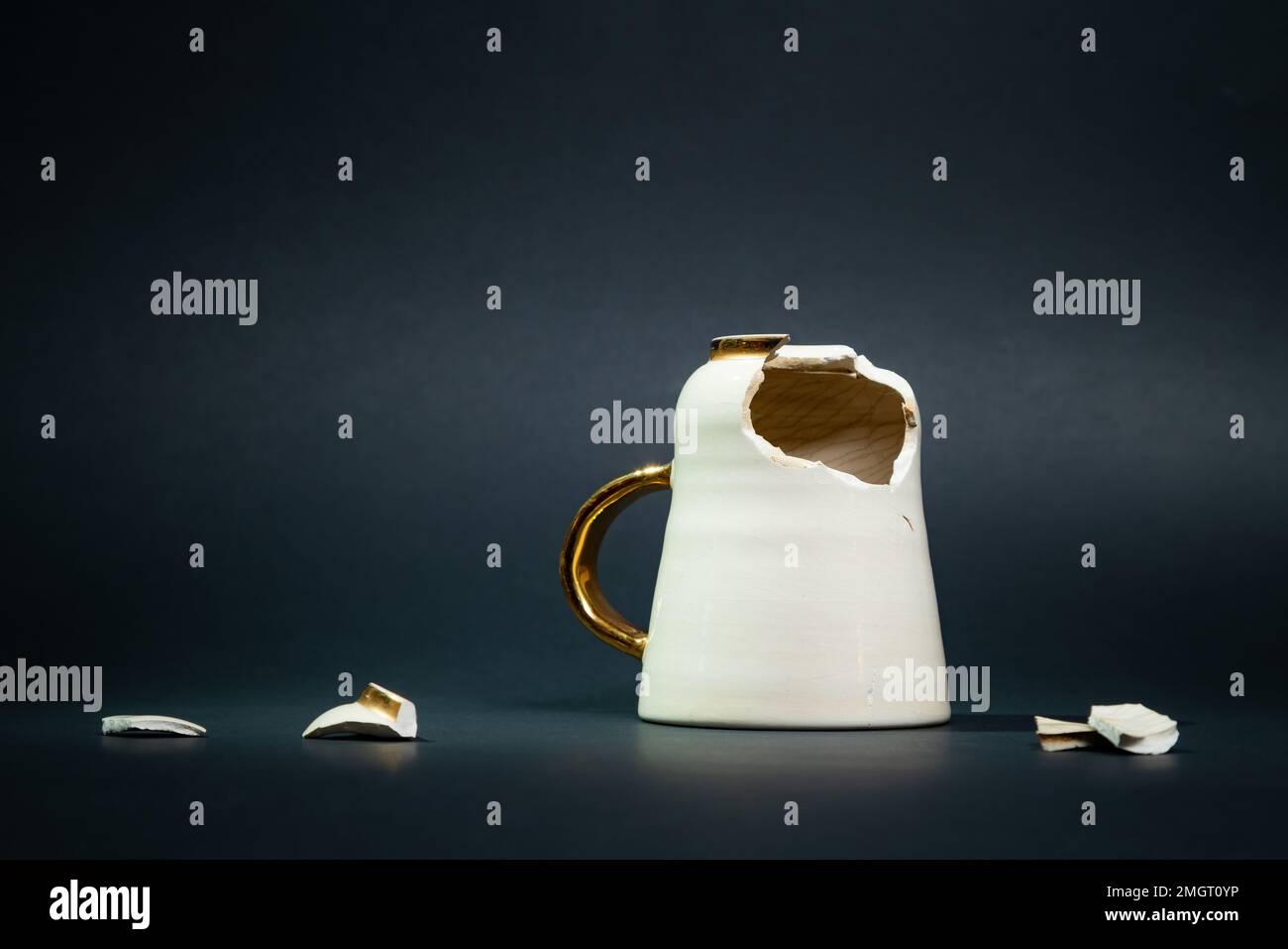 Broken tea cup isolated on black background. Cracked coffee mug and fragile ceramic pieces Stock