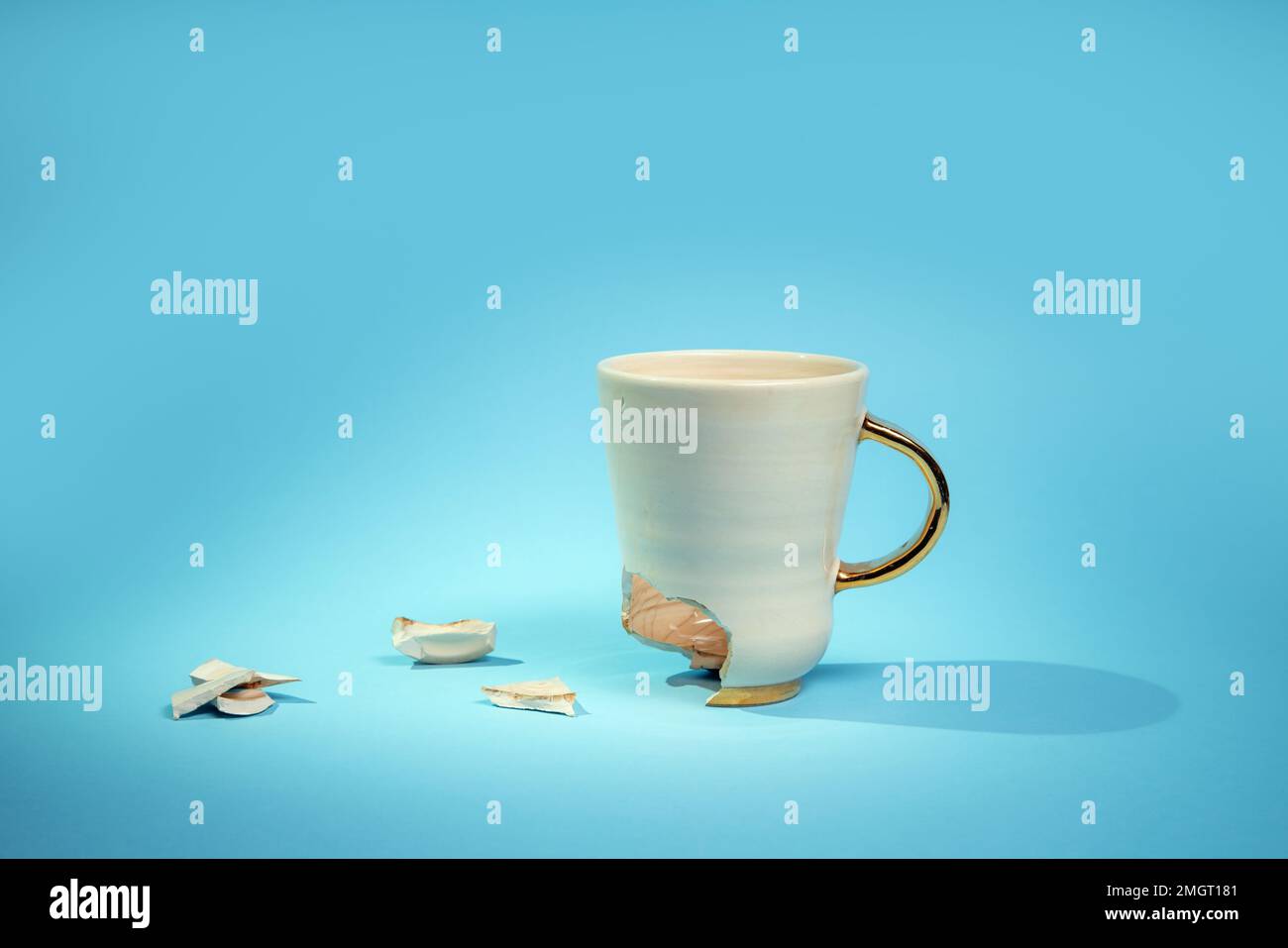 Broken tea cup isolated on blue background. Cracked coffee mug and ...