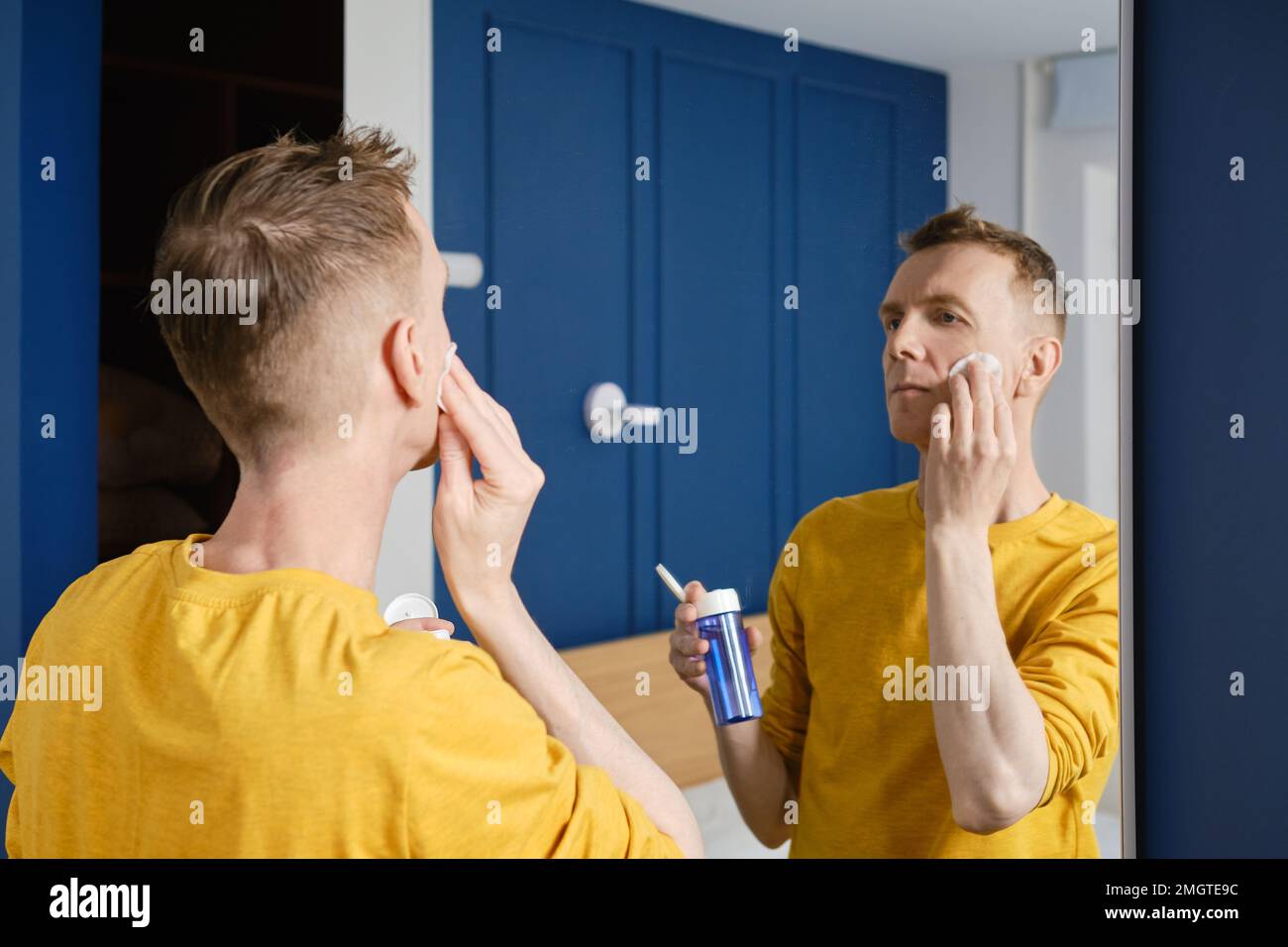 Middle aged man cleaning face with lotion using cotton pad Stock Photo