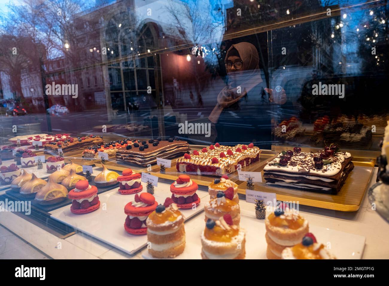 Waitress serving sweet patisserie, cakes and pastries in a shop window