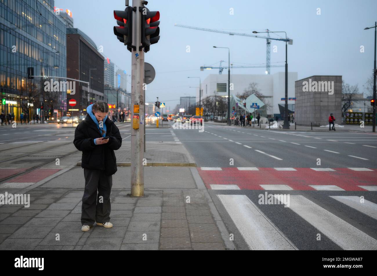 Warsaw, Poland. 25th Jan, 2023. A young woman wearing a blue hoody is seen using her mobile phone at a street crossing in Warsaw, Poland on 26 January, 2022. More than 500 ideas have been submitted by citizens for the yearly participatory budget of the city of Warsaw. Every year since 2015 citizens are offered the opportunity to hand in proposals for projects as long as they are supported by at least 20 other inhabitants. (Photo by Jaap Arriens/Sipa USA) Credit: Sipa USA/Alamy Live News Stock Photo