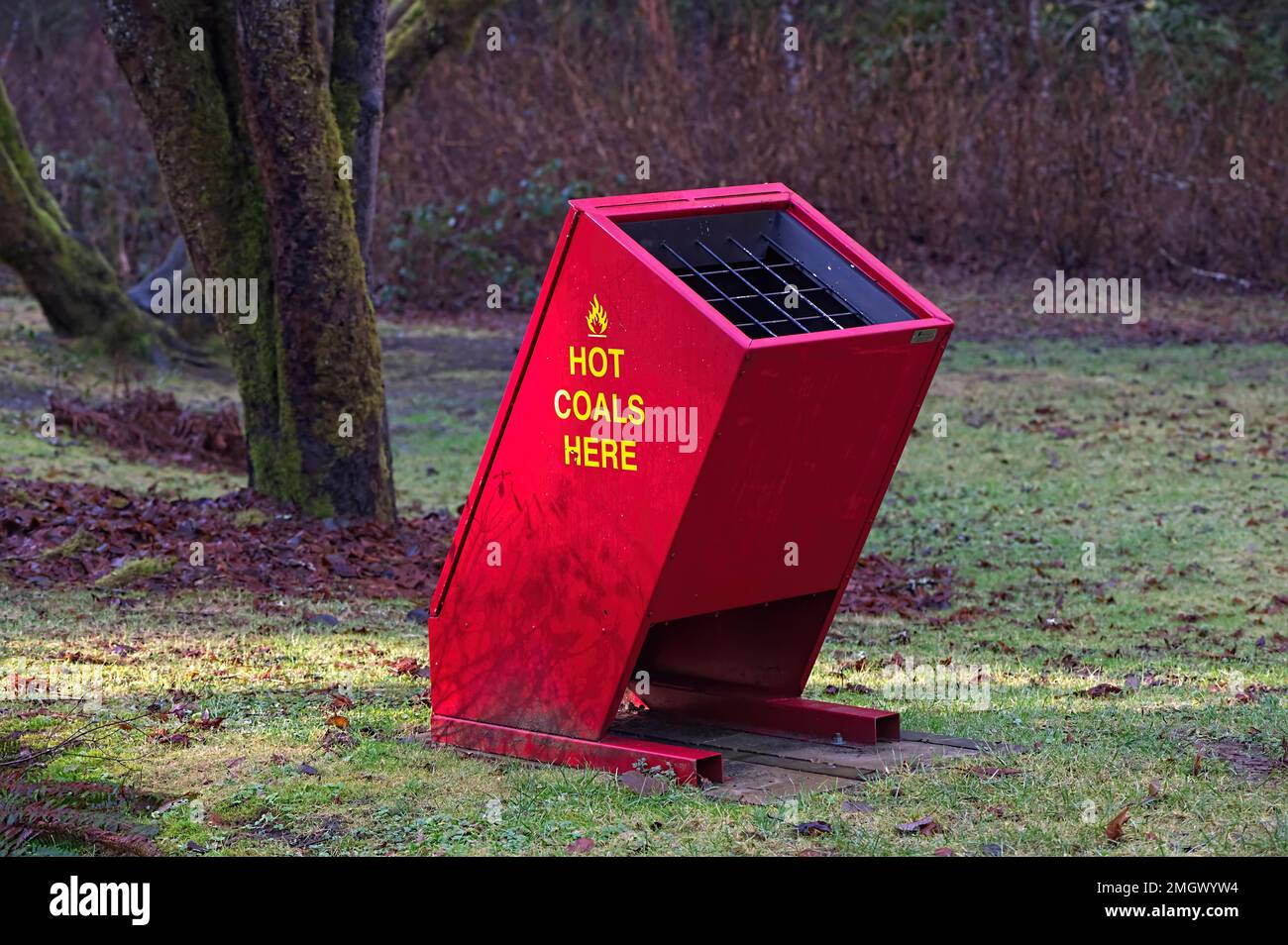 Bright red hot barbecue coal receptacle with yellow lettering in the picnic area of a local park - Maple Ridge, B. C., Canada. Stock Photo