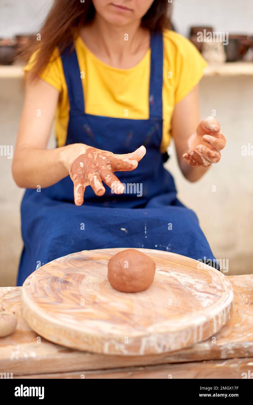 craftswoman's hands throw piece of clay on potter's wheel. Cropped