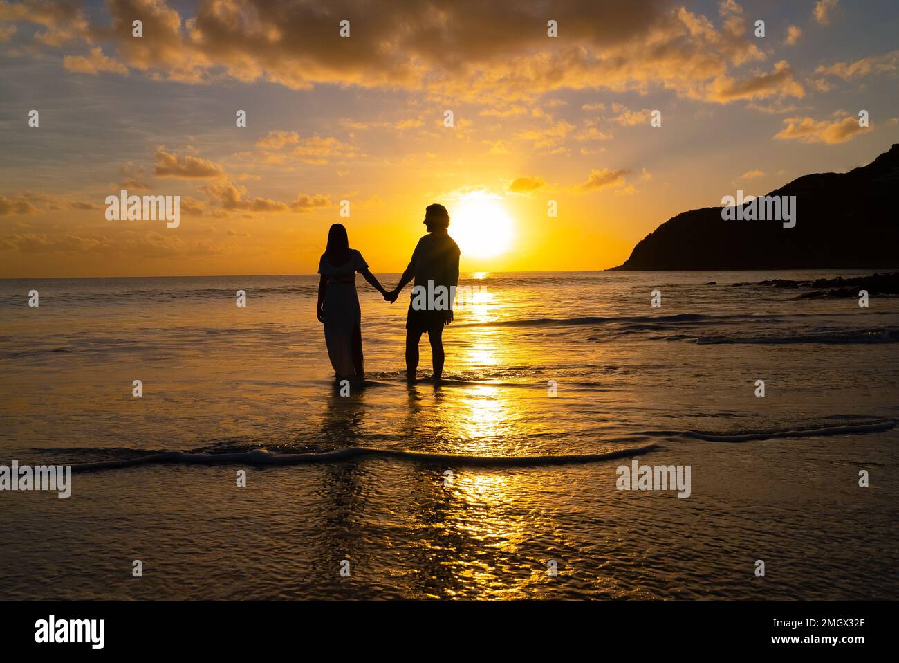 Silhouette of couple holding hands during the sunset on a tropical ...