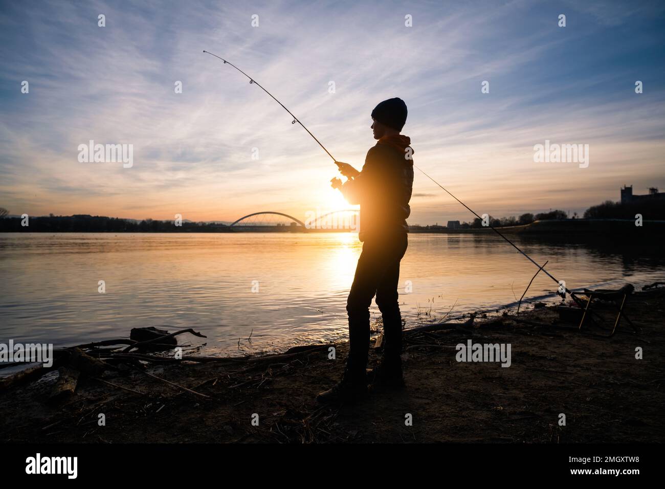Silhouette of boy fishing at sunset hi-res stock photography and