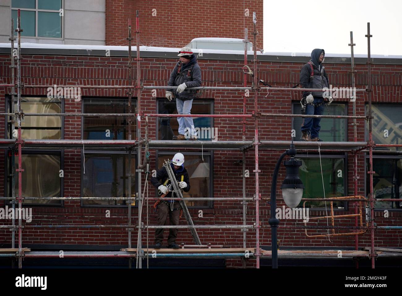 Workers erect scaffolding around a building Wednesday, Jan.25, 2023, in