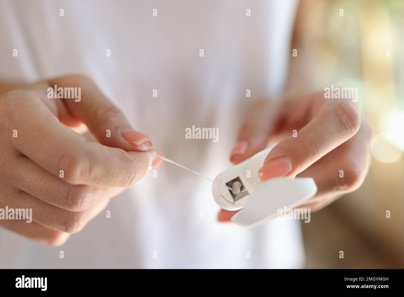 Women's hands pull out the dental floss close-up. Stock Photo