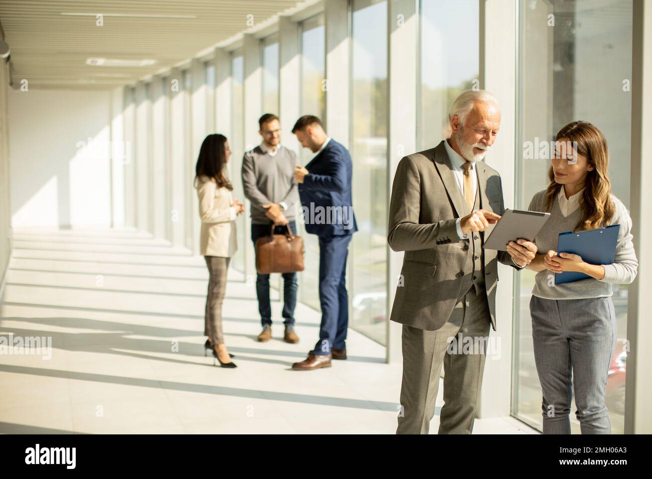 Handsome senior business man with his young female coleague using digital tablet in the office Stock Photo