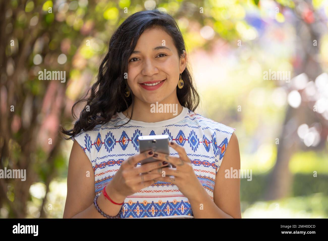 Real Mexican woman holding smart phone and looking at camera Stock Photo