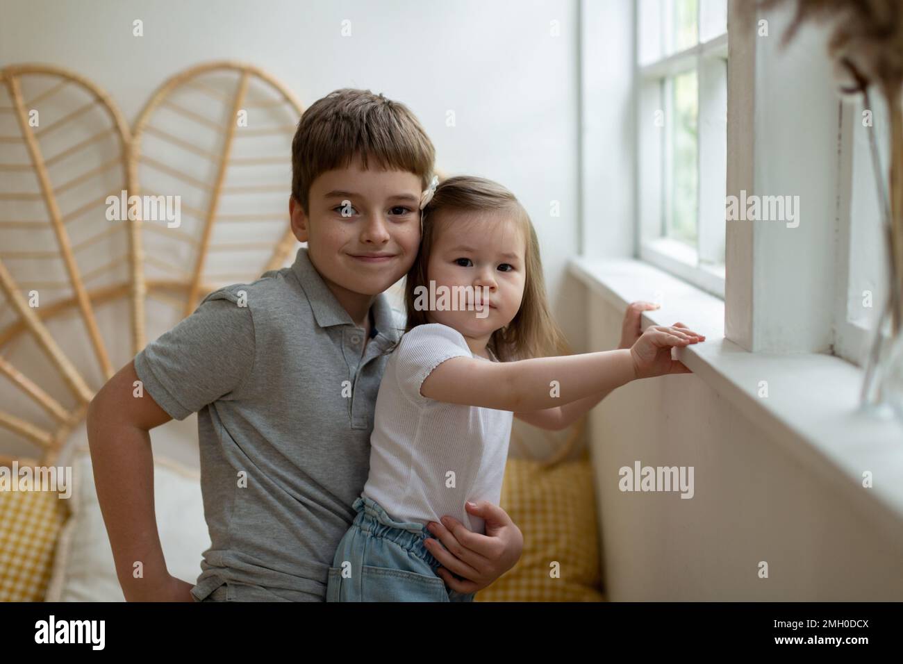 Big brother schoolboy hugs his little sister Stock Photo