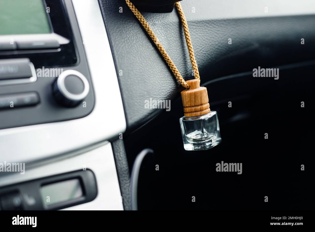 Small aroma glass jar car air freshener hanging on dashboard in vehicle saloon Stock Photo
