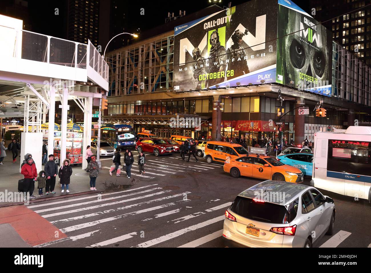 Busy street junction in Manhattan New York .Taxi cabs queueing at junction between 8th Avenue and 42nd Street with pedestrians at crossing. Night view Stock Photo