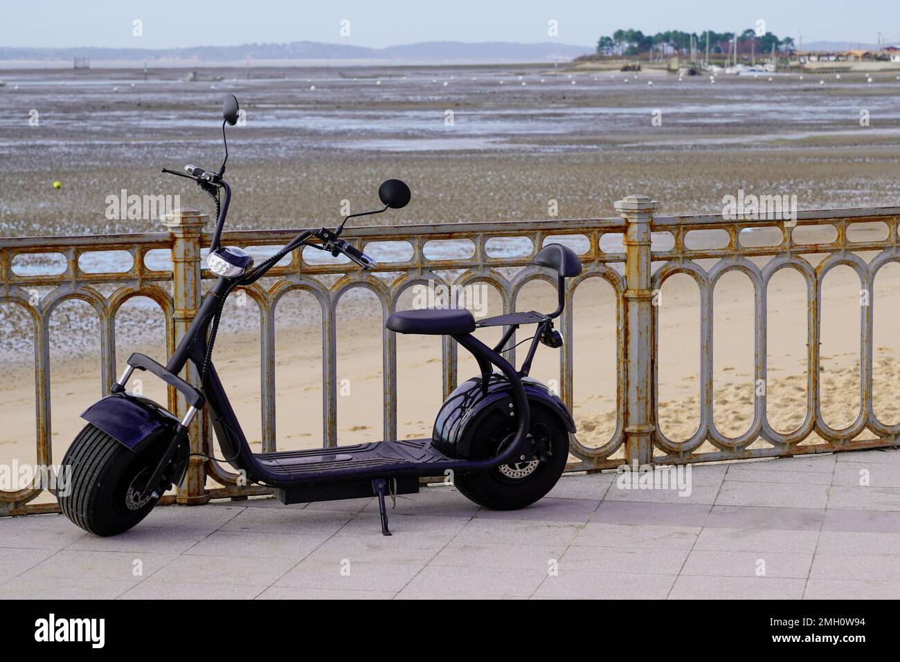 Two wheeled electric black scooter with large wide wheels on sea side