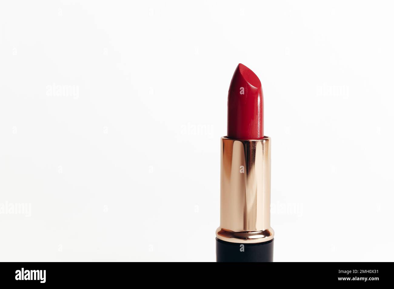 Isolated new red lipstick without cap in a golden container on a white background, macro photo Stock Photo