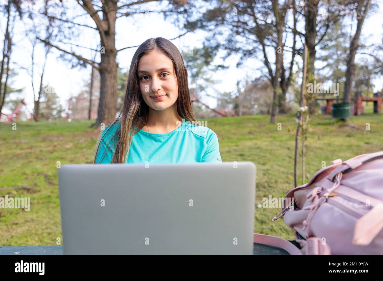 Female university student studying, using a laptop and sitting outside in a park. Looking at camera Stock Photo