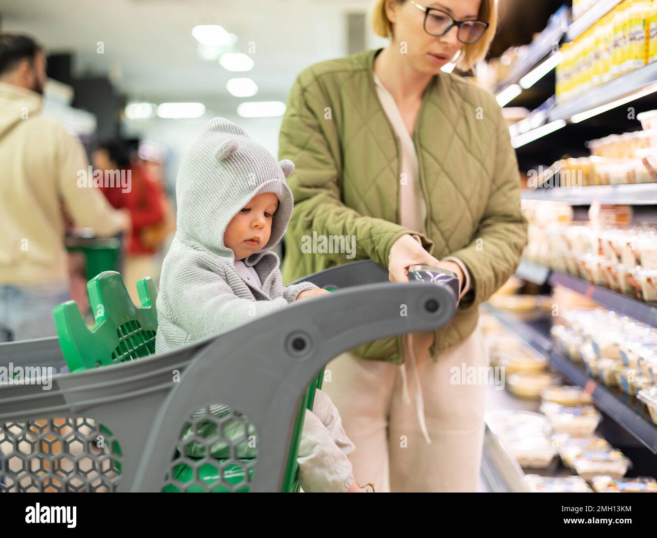 Casualy dressed mother choosing products in department of supermarket ...