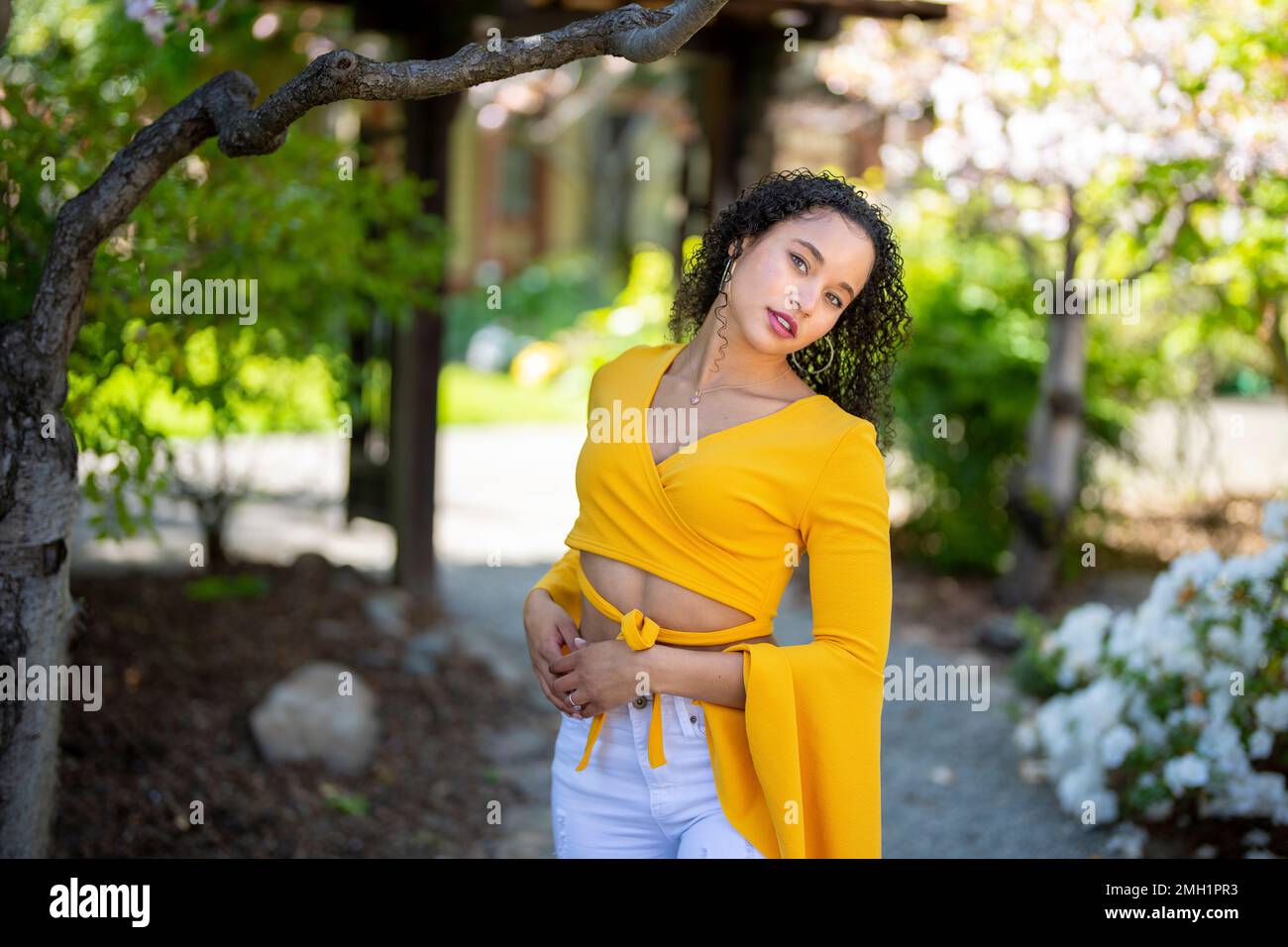 Half Body Portrait of Young African American Woman Standing on Pathway in Japanese Style Garden with Arms at Side - Spring Stock Photo