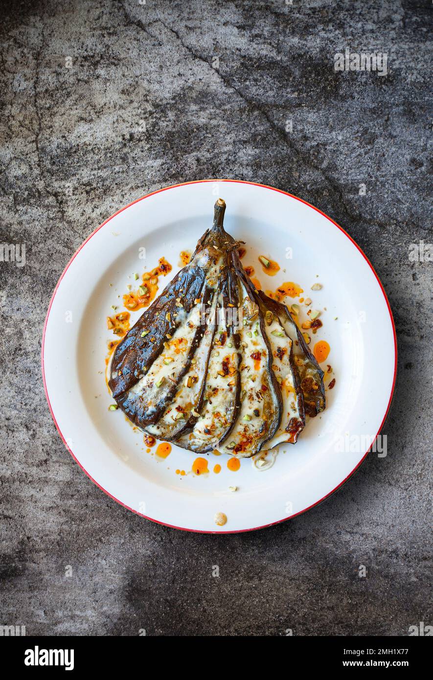 Baked Eggplant, dressed with harissa and pistachio. Stock Photo
