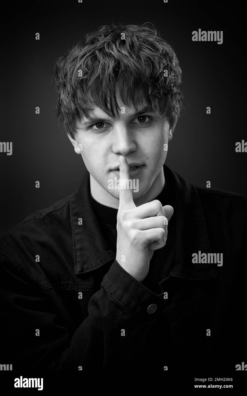 handsome man asking to be quiet with finger on lips. Stock Photo