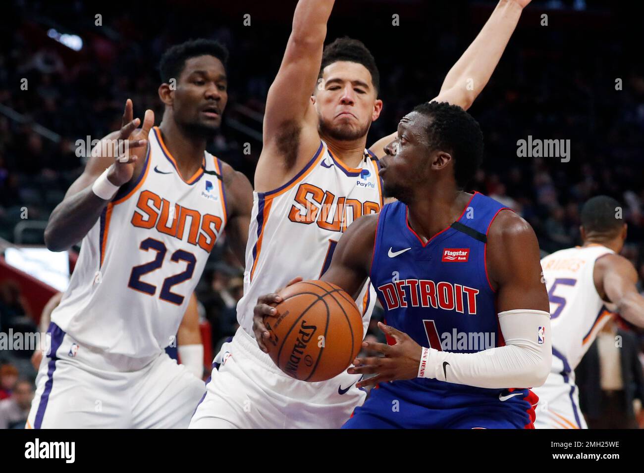 Detroit Pistons guard Reggie Jackson (1) is defended by Phoenix Suns guard Devin Booker (1) and center Deandre Ayton (22) during the second half of an NBA basketball game, Wednesday, Feb. 5, 2020, in Detroit. (AP Photo/Carlos Osorio) Stock Photo