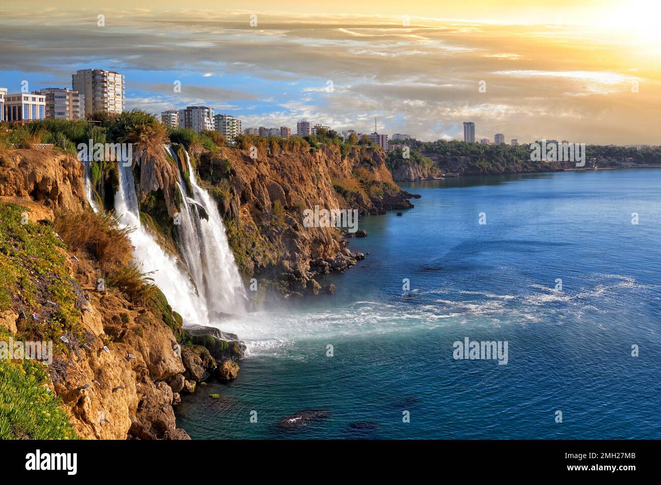 Picturesque morning landscape of the Lower Duden waterfall against the backdrop of the steep shores of the Mediterranean Sea and urban development in Stock Photo