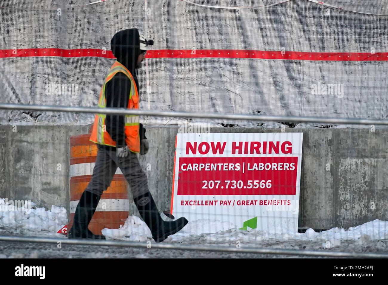 A construction worker passes a hiring announcement sign at the site of