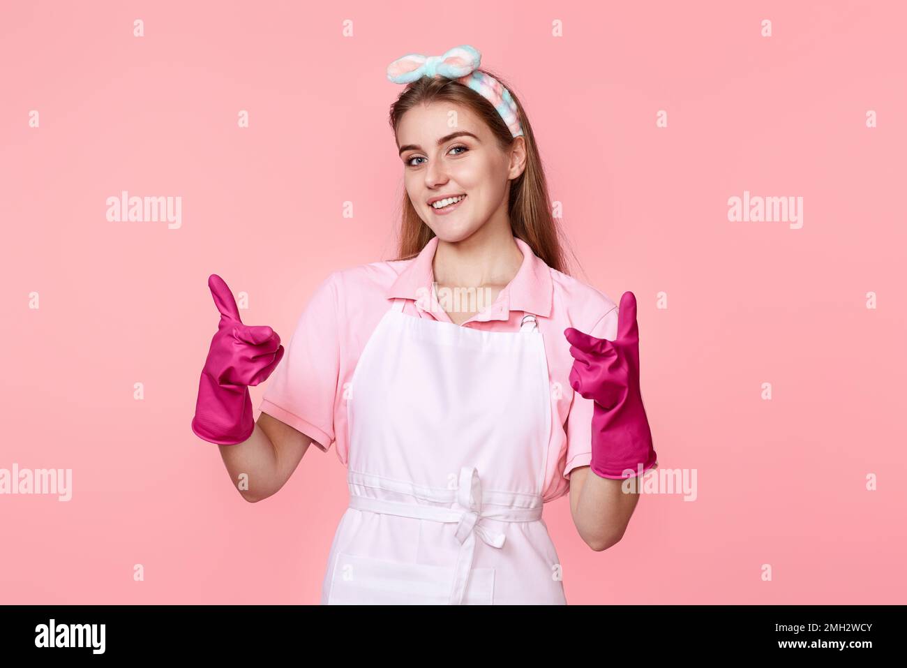 woman in rubber gloves and cleaner apron pointing fingers to camera Stock Photo