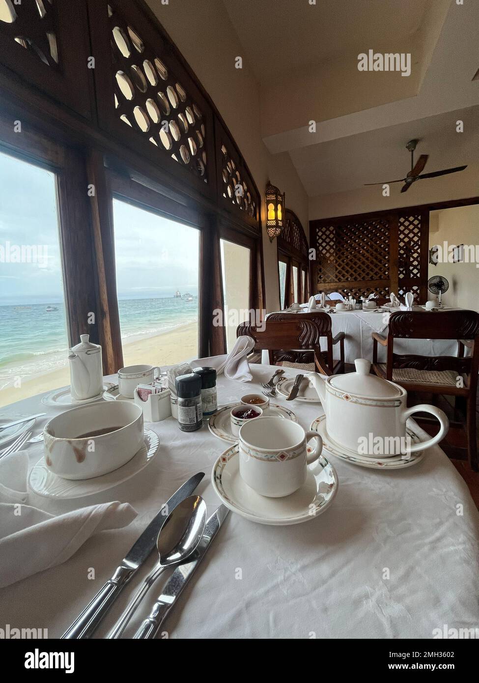 Tourism has tea time in front of the beach and breakfast in the hotel restaurant or buffet with a beach window view. Zanzibar, Tanzania. Stock Photo