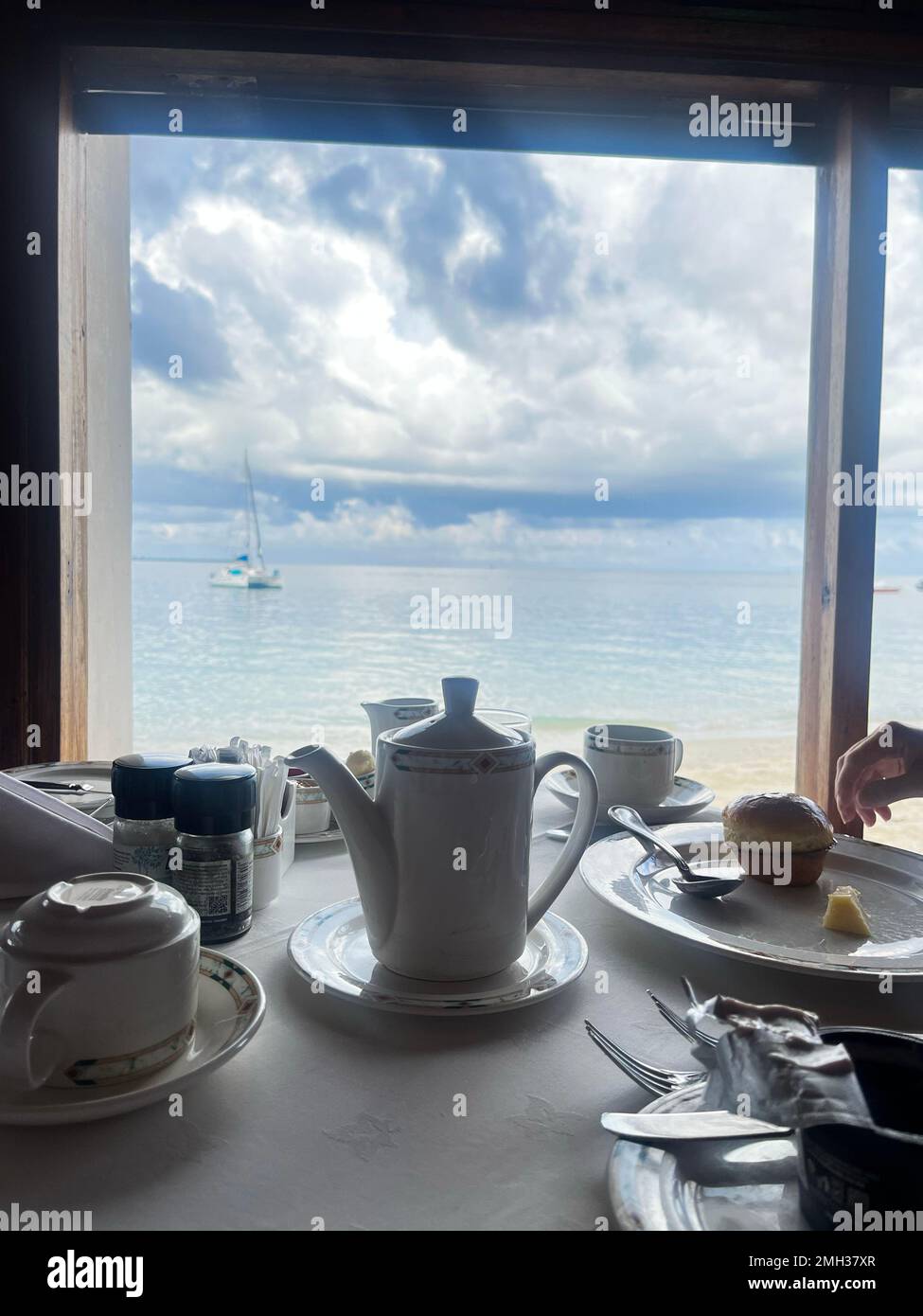 tourism having tea time in front of the beach, afternoon tea time in the hotel with beach window view. Zanzibar, Tanzania. Stock Photo