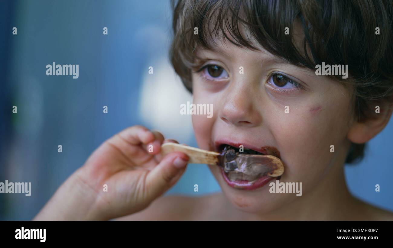 Closeup child face finishing icecream dessert. Messy young boy mouth