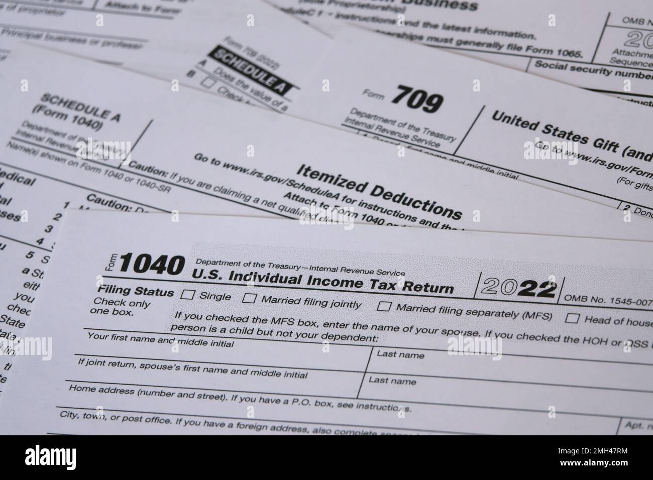 For tax year 2022, an IRS 1040 tax form is shown, along with Itemized Deductions (Schedule A) and Gift (form 709) worksheets for filing in 2023. Stock Photo