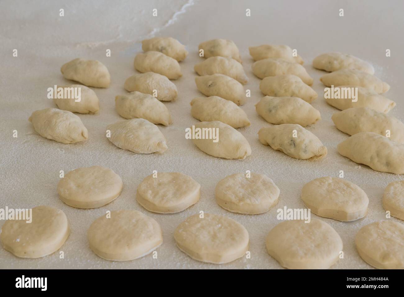 Getting ready to bake buns with stuffing and donuts from yeast dough on white counter before