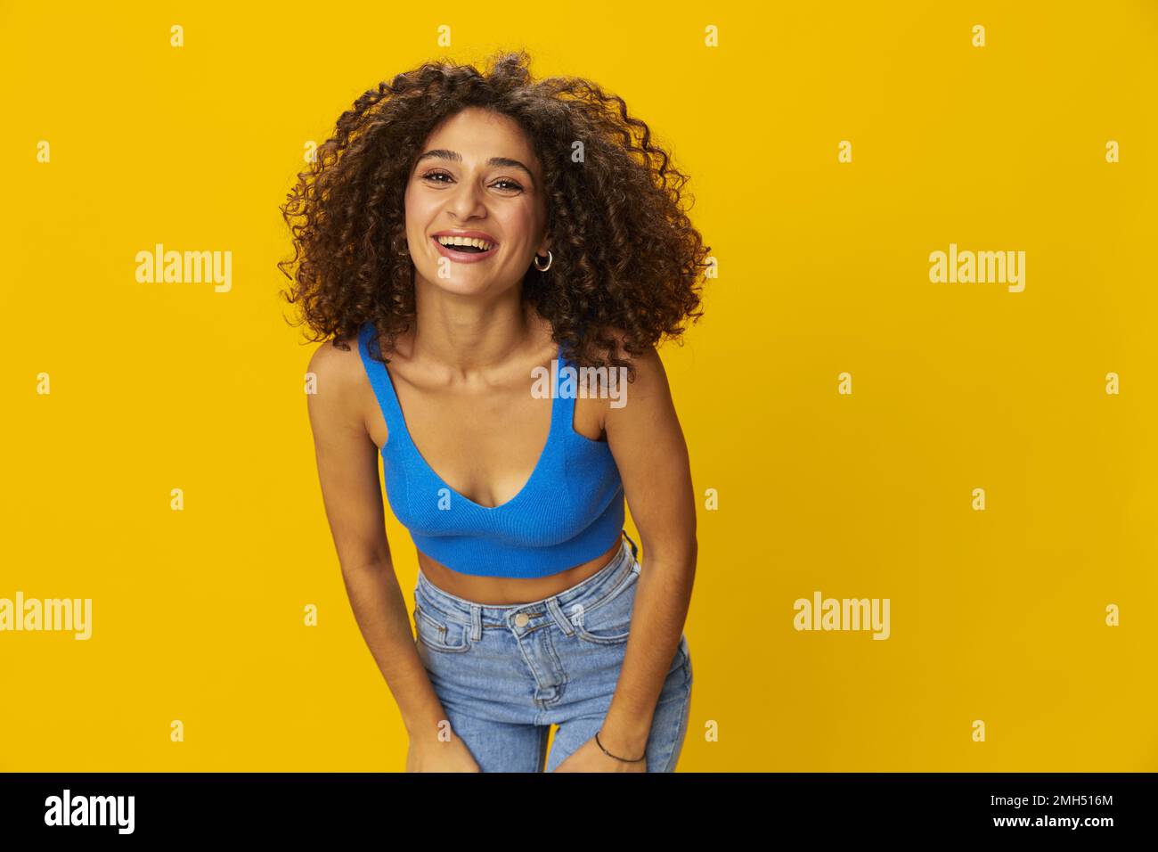 Woman with curly afro hair in a blue t-shirt on. yellow background signs with her hands, look into the camera, smile with teeth and happiness, copy Stock Photo - Alamy Woman with curly afro hair in a blue t-shirt on. yellow background signs with her hands, look into the camera, smile with teeth and happiness, copy Stock Photo - Alamy