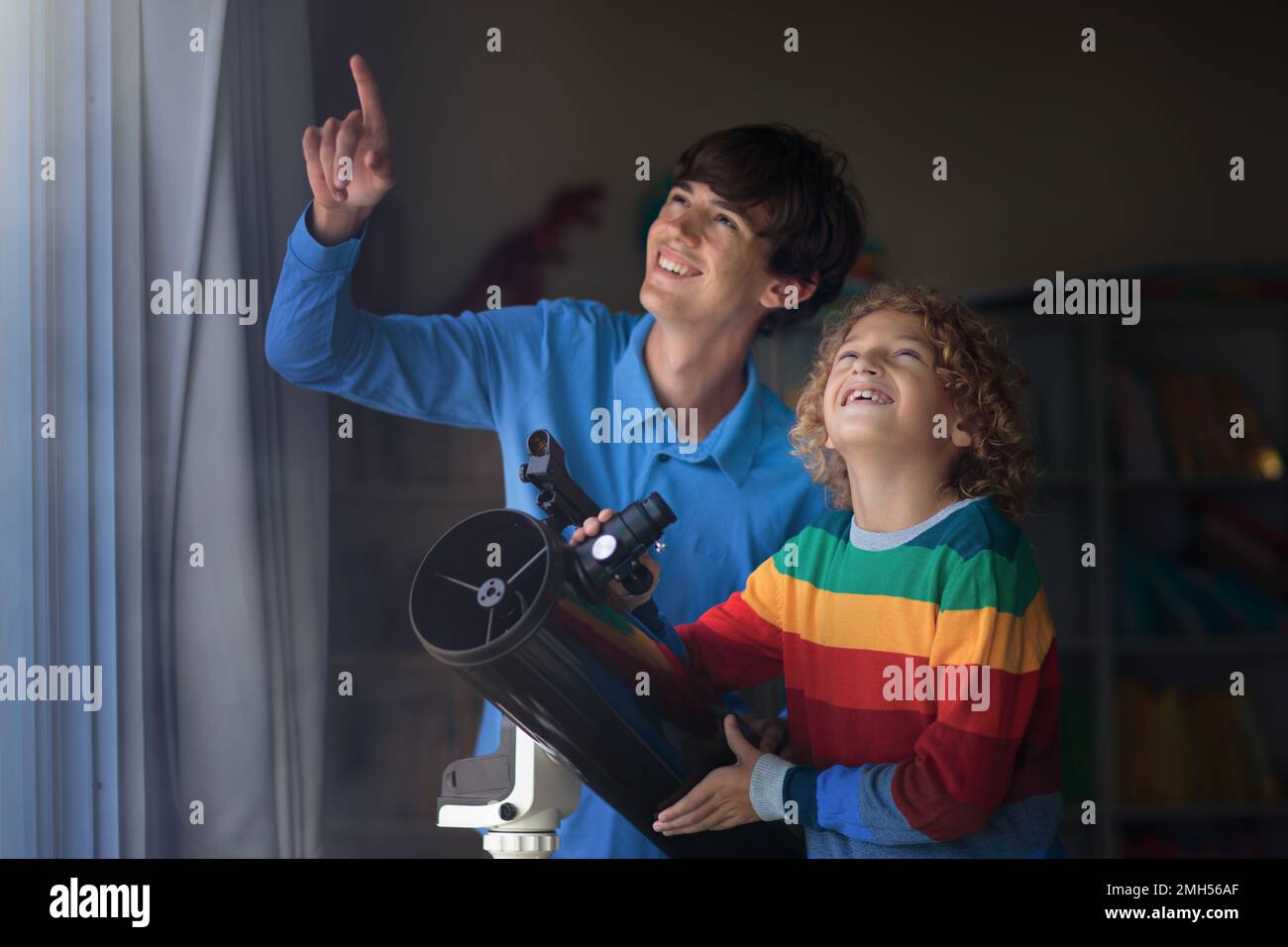 Little boy and young man looking at stars through telescope. Child and parent watching night sky and moon. Astronomy science for explorer kid. Stock Photo