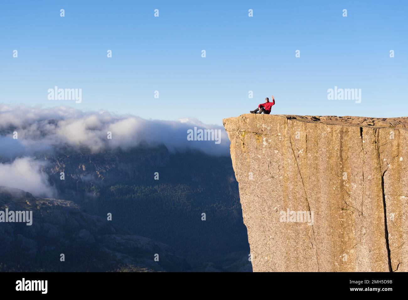 Preikestolen - amazing rock in Norway. Guy sitting on a cliff above the ...