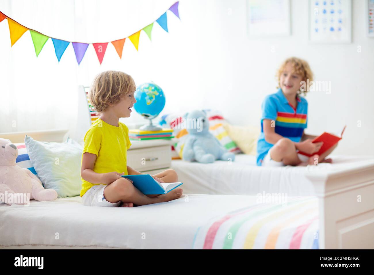 Child reading book in bed. Bedroom for two kids. Little boys read books