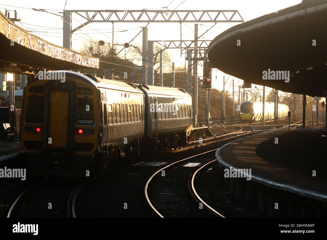 Northern trains express sprinter dmu waiting in Carnforth station, 25th January 2023, while Avanti West Coast pendolino passes on West Coast Main Line. Stock Photo