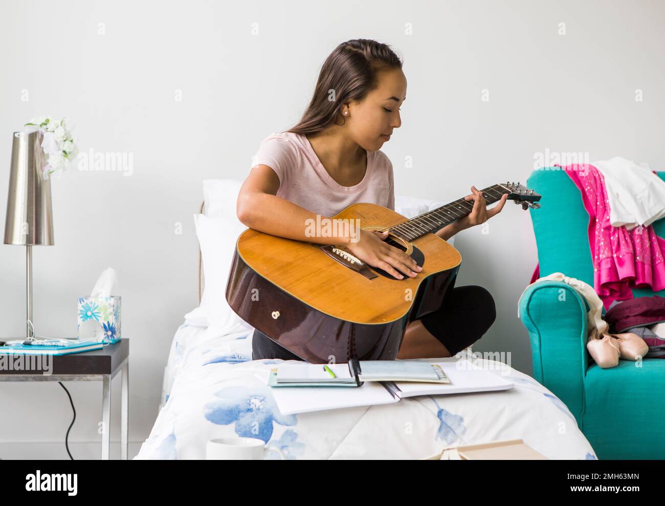 A teenage girl playing guitar in her bedroom. Stock Photo
