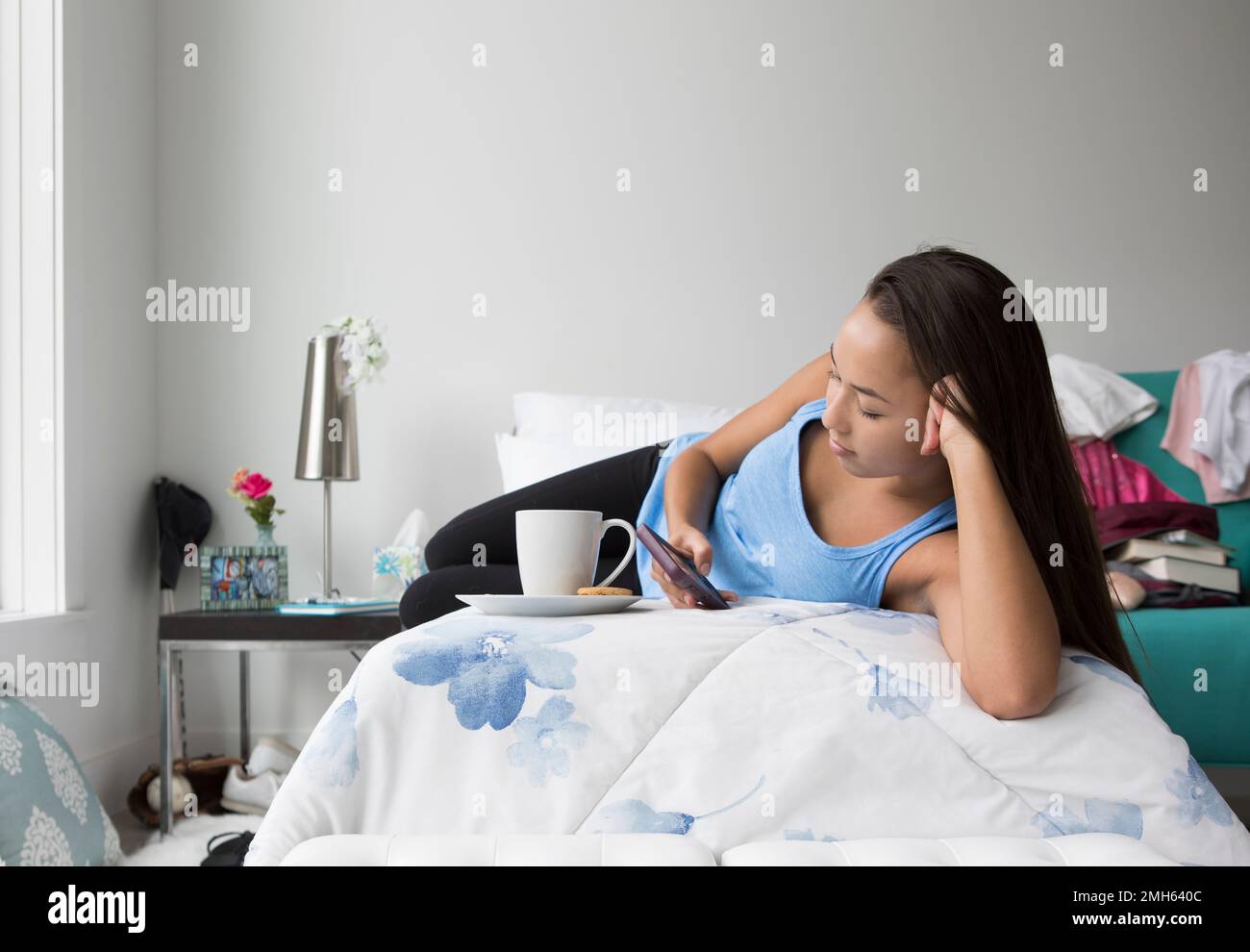 A teenage girl looks at her mobile phone in her bedroom Stock Photo - Alamy