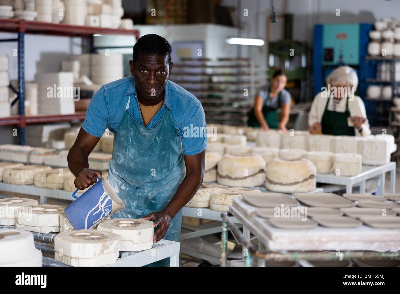 Slip casting african american worker pours slip mass from jug into