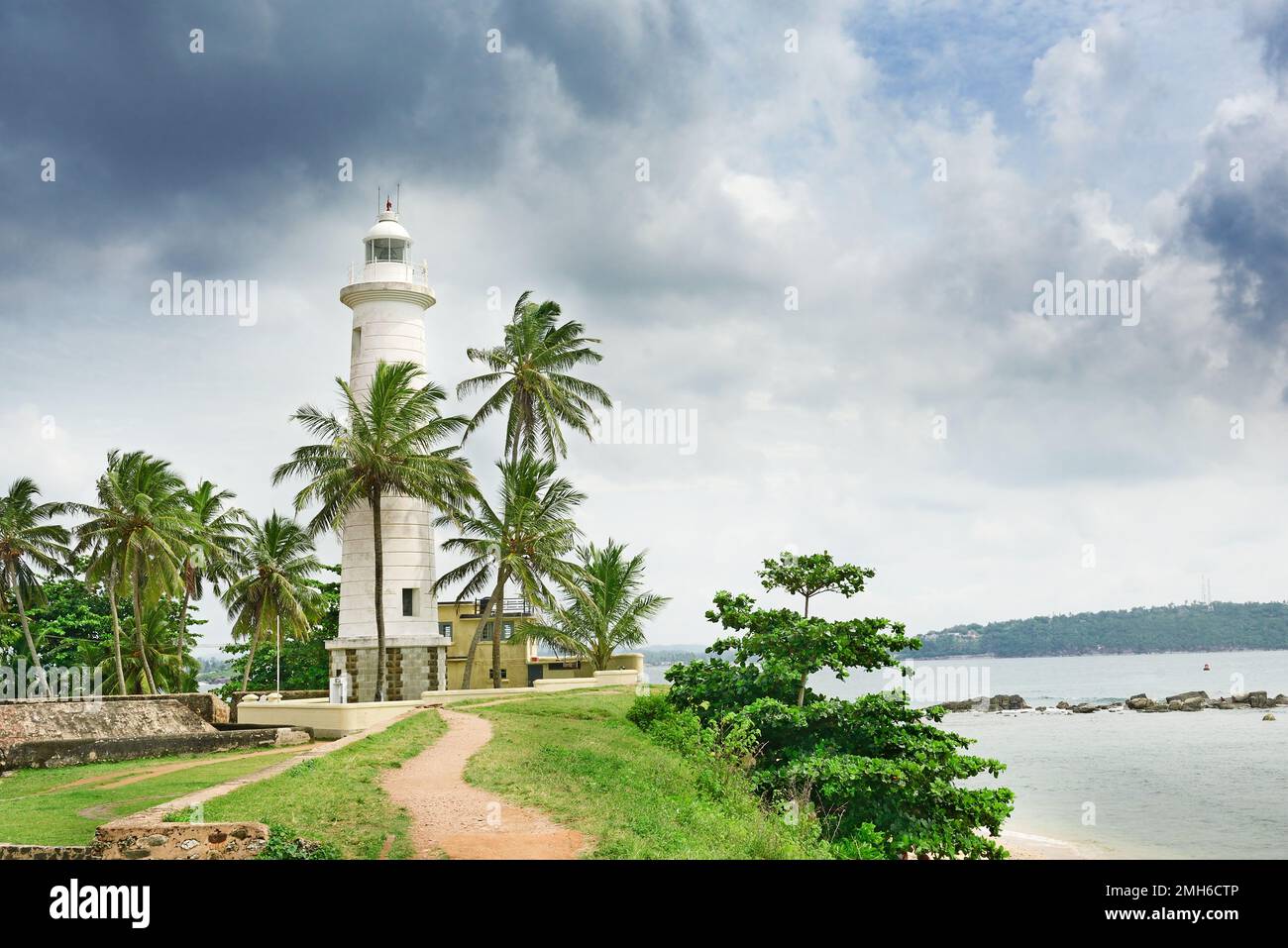 Lighthouse and palm trees on background sky. Stock Photo