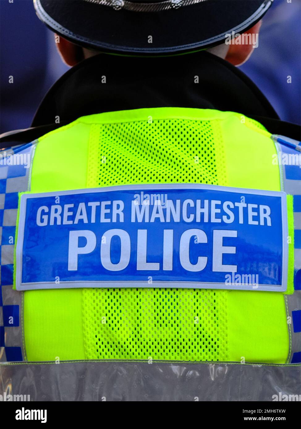 Police officer from behind showing high viz vest with the words Greater Manchester Police on a blue badge Stock Photo